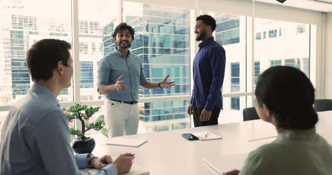 Indian male boss congratulate with promotion African employee, welcoming newcomer, praising, shake hands, express respect for great work done, get rewarded engaged in briefing. Business achievements
