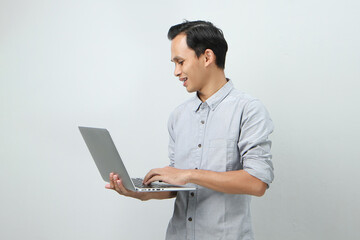 happy asian indonesian man holding laptop computer on isolated background