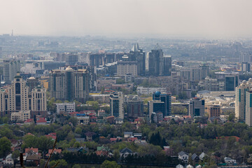 Combination of low-rise and high-rise urban development. Panoramic view on Almaty from mount Kok Tobe park. Cityscape at spring day. Haze smog above town, ecology problem. Republic of Kazakhstan