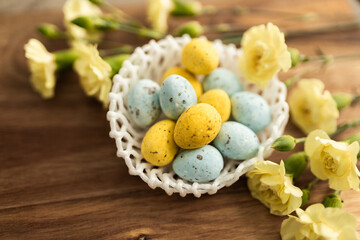 Yellow flowers and pastel yellow and blue colored eggs in a white small wicker basket on a background of brown wood. Layout. Mockups. Pastel Springs background. Easter background. Easter eggs close up