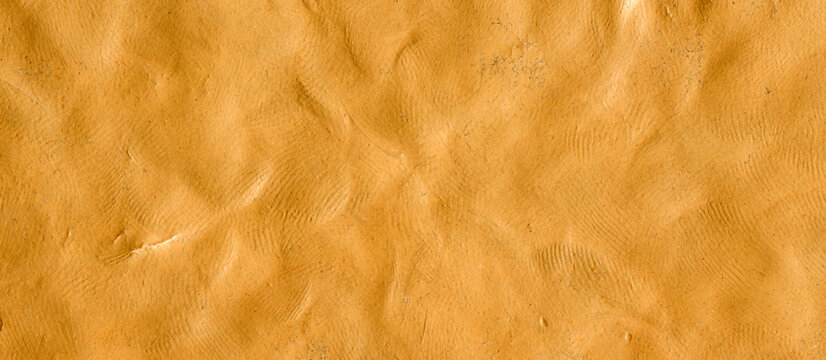 Orange colored plasticine texture. Ochre playdough textured background. Abstract sienna clay backdrop. Templates of web banner, handmade poster design or label design elements. Natural 3d relief.