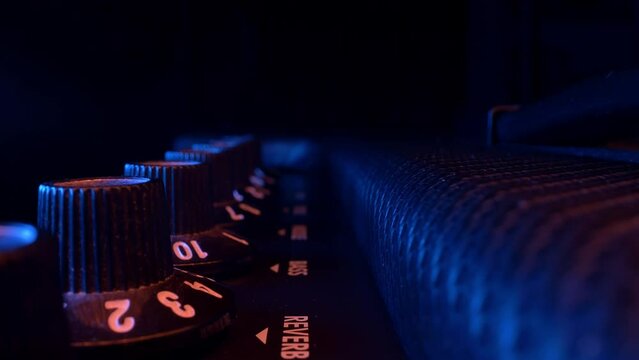 Adjusting knobs on a electric guitar amplifier tracking shot