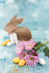 Pink flowers and yellow and white colored easter eggs, and easter bunny on a blue picturesque oil painting background close up. Spring Mockups.Layout. Easter pastel background