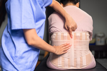 Physiotherapist treat senior women patient orthopedic corset at clinic
