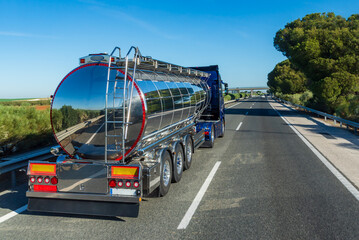 Tanker truck with shiny aluminum exterior for transporting food liquids traveling on a highway,...
