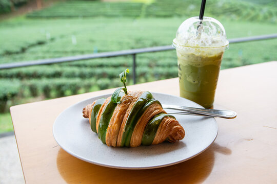 Matcha green tea  with croissant on the wooden table at  Choui Fong tea plantation  in Chiang Rai province, Thailand