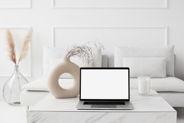 Laptop computer with empty blank mockup screen over white modern living room design. Advertisement, e-learning, shopping online, web site design, technology concept - 749819191