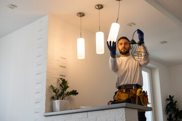 Electrician worker installation electric lamps light inside apartment. Construction decoration...