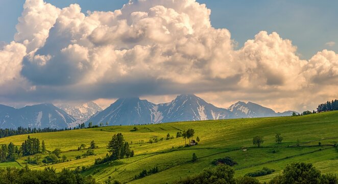 Spring green mountain landscape with meadows and rocky peaks. Landscape with a chapel and snow-covered Tatra Mountains in Kacwin, Malopolskie, Poland