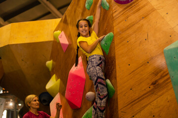 little girl climbing a rock wall indoor