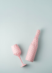 Champagne bottle with glass packaged in pink polka dot gift paper on blue pastel background with...