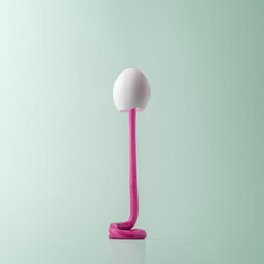 Creative Easter concept. White egg in the form of a rocket with pink paint on a blue background.