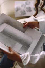 Close up shot of girl artist looking at paintings. Pencil drawings. Learning to draw