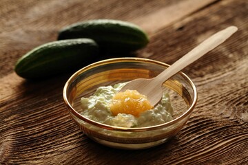 Facial mask from cucumber, yogurt and honey for perfect skin. Edible ingredients for facial mask on the brown wooden board.