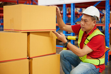 factory worker or warehouser checking corrugated boxes in the warehouse storage