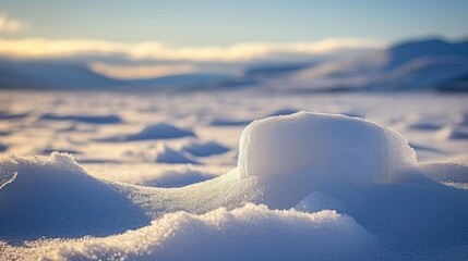 a pile of snow sitting in the middle of a snow covered field with mountains in the distance in the distance.