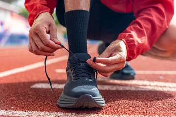 Close up male runner tied the rope, prepare jogging shoes on running track background, outdoor...