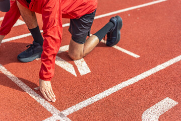 Close up runner man using starting block to start his run on running track background, outdoor...