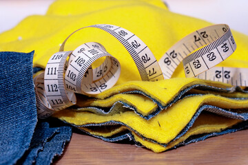 A measuring tape with fabrics in yellow fleece and denim.