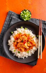 Kimchi with pork on cooked rice, traditional Korean cuisine. Orange background