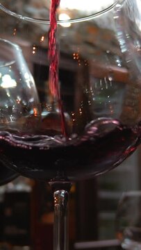 This stock video in vertical format shows wine glasses in which red wine is poured. This video will decorate your projects related to holidays, alcoholic beverages.