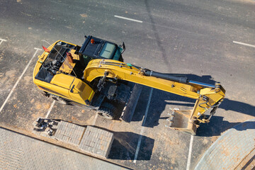 A bright yellow construction vehicle is seen parked in a parking lot under the sun