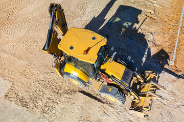 Universal excavator or loader with folded bucket at construction site. Universal construction equipment. Rental of construction equipment. Contract for construction work.