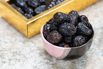 Ajwah dates in a ceramic bowl on a white wooden background are the best fruits of Medina.