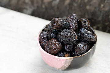 Ajwah dates in a ceramic bowl on a white wooden background are the best fruits of Medina.