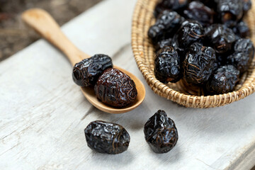 Dried ajwa dates in a wooden bowl on a white wooden background are food for breaking the fast during the Islamic month of Ramadan.