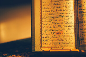 The Quran was opened for reading and had a dim golden glow. Selective focus. The concept of Islam.