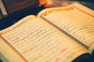 The Quran was opened for reading and had a dim golden glow. Selective focus. The concept of Islam.