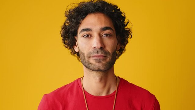 Close up, man looking at camera isolated on yellow background in studio