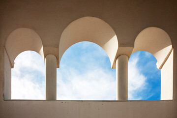 Three arches, bottom view. Three arched doorways and blue sky with clouds. stone arched windows...