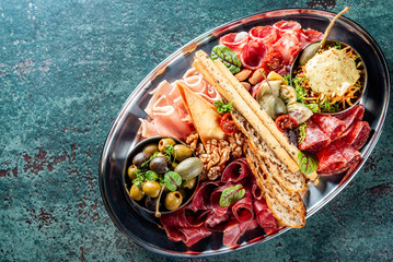 A gourmet charcuterie platter with assorted meats, olives, and bread is elegantly presented on a...
