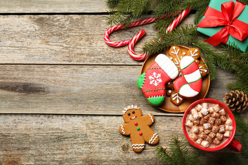 Different tasty Christmas cookies, decor and cocoa with marshmallows on wooden table, flat lay. Space for text