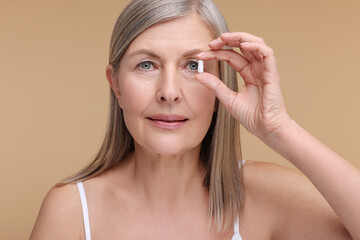 Fototapeta premium Beautiful woman with vitamin capsule on beige background