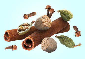Cinnamon sticks and other aromatic spices falling on light blue background