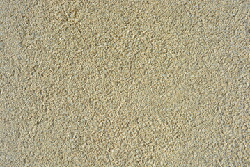 Yellow bright background, construction wall with very small glass stones matte white and gray with a reflection of the sun.