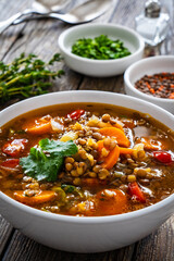 Fresh vegetable soup with lentil on wooden table
