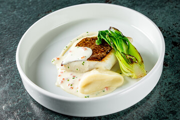 “Elegantly plated grilled fish with bok choy and creamy sauce on a white dish.” The golden-brown seared fish contrasts beautifully with the green bok choy, all set against a white plate. - obrazy, fototapety, plakaty