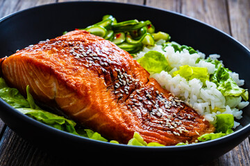 Fried teriyaki salmon steak with white rice and sliced cucumber on wooden table
- 749870317