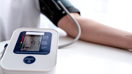 the girl measures blood pressure with a blood pressure monitor