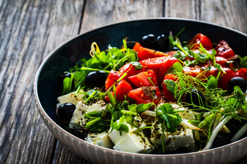 Greek style salad - fresh vegetables with feta cheese on wooden table

