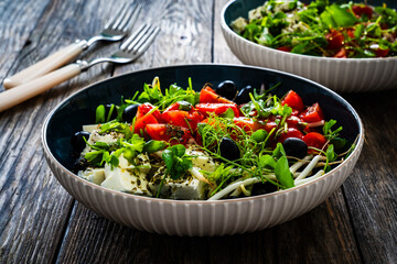 Greek style salad - fresh vegetables with feta cheese on wooden table

