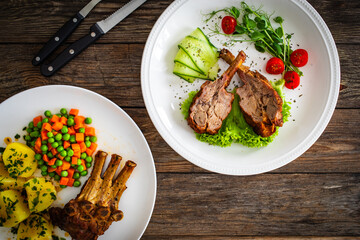 Lamb chops with bone and fresh vegetables on wooden table