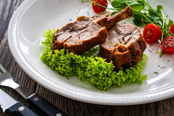 Lamb chops with bone and fresh vegetables on wooden table