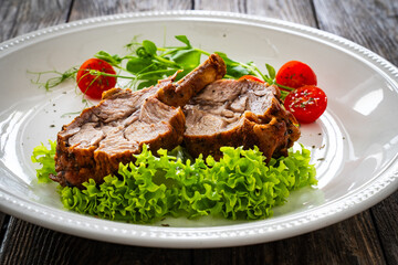 Lamb chops with bone and fresh vegetables on wooden table