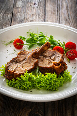 Lamb chops with bone and fresh vegetables on wooden table