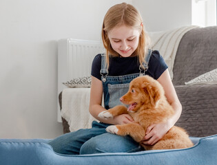 Small Girl With Toller Puppy Sits In Blue Dog Bed, Nova Scotia Duck Tolling Retriever